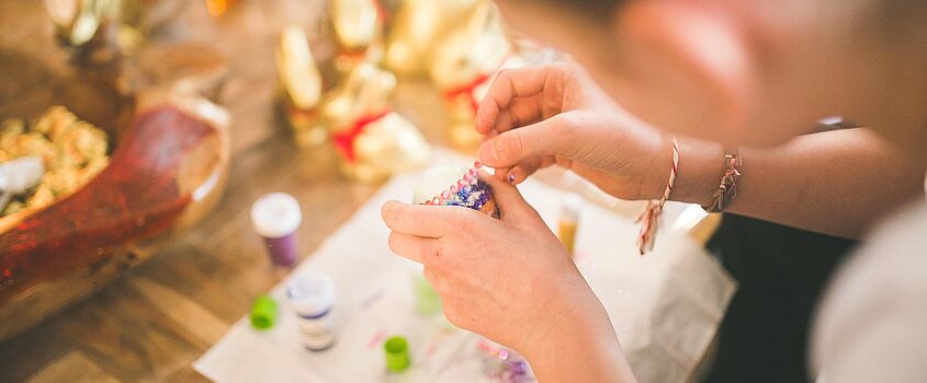 Kind bemalt ein Osterei